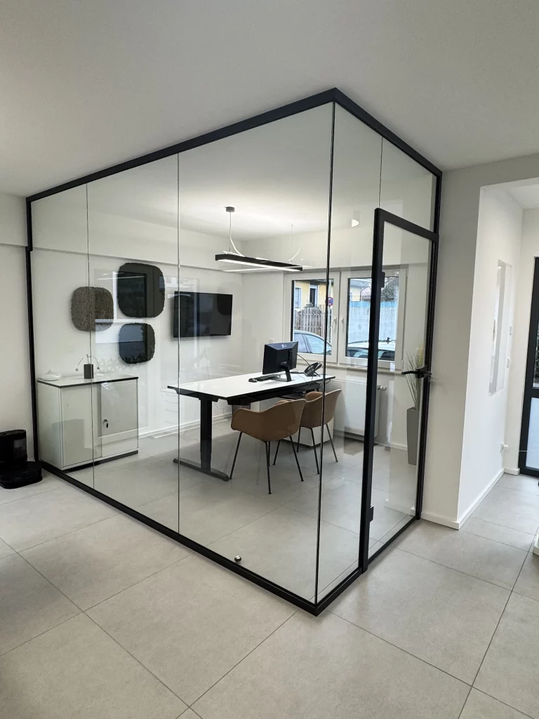 Glastrennwand in L-Form mit integrierter Türanlage und anthrazitfarbener Aluminiumzarge. Die Konstruktion verbindet architektonische Klarheit mit funktionaler Raumtrennung – ideal für hochwertige Büroprojekte in Köln