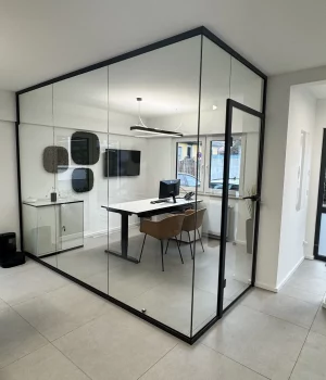 Glastrennwand in L-Form mit integrierter Türanlage und anthrazitfarbener Aluminiumzarge. Die Konstruktion verbindet architektonische Klarheit mit funktionaler Raumtrennung – ideal für hochwertige Büroprojekte in Köln